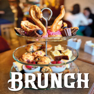 Dozens of fancy pastries arranged on a three-tiered glass platter at Adorable Chocolat, in Shediac, NB. The pastries include mousse-filled chocolate cups, chocolate-dipped madeleines, raspberry swans, lemon cake, cranberry scones, and a tier of salty treats on the bottom.