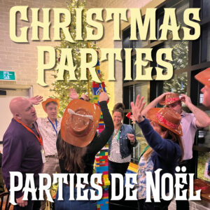 A group of coworkers participate in team-building exercises in front of a Christmas tree.