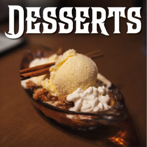 An apple crisp à la mode served with whipped cream is presented in a glass dish on a wooden table at Le Moque-Tortue.