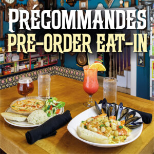 Two meals are waiting for their guests on a wooden table at Le Moque-Tortue. Accompanying the meals are two glasses of water, a glass of beer and a Shirley temple in a hurricane glass.